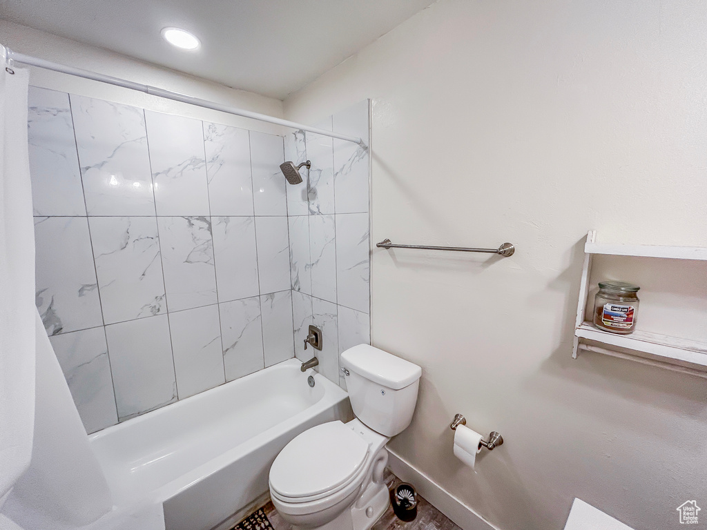 Bathroom featuring toilet, shower / bathtub combination, and baseboards