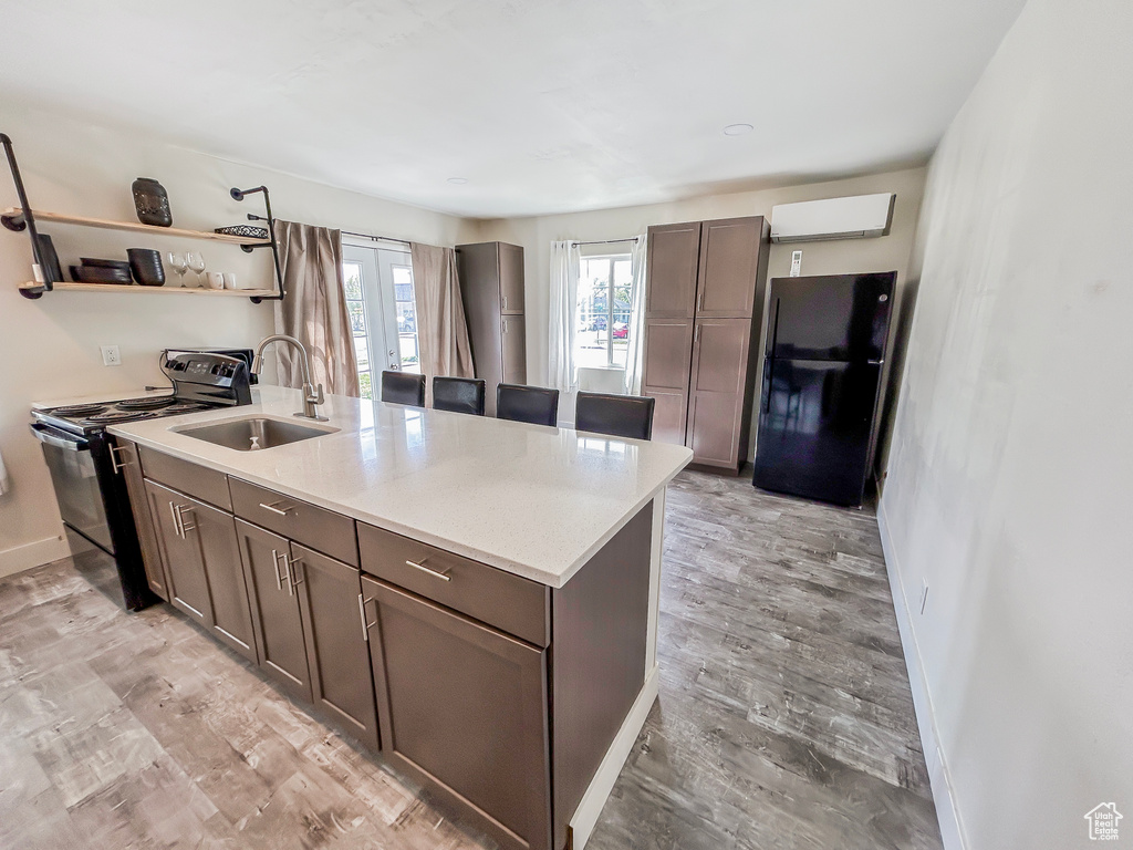 Kitchen with open shelves, light countertops, black appliances, a sink, and baseboards