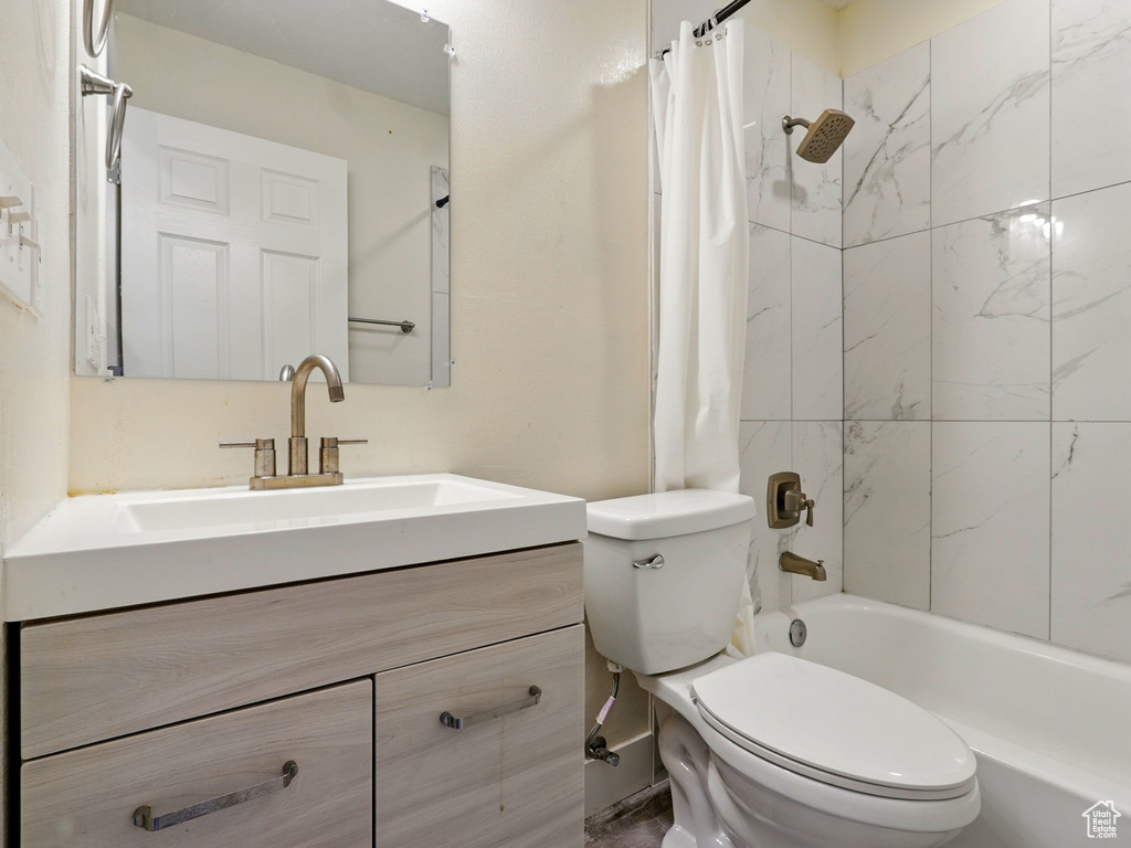 Full bath with toilet, shower / tub combo with curtain, and vanity