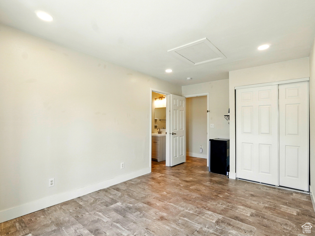 Unfurnished bedroom with attic access, recessed lighting, wood finished floors, baseboards, and a closet