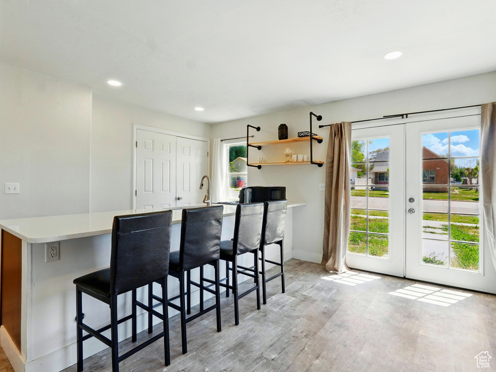 Kitchen with plenty of natural light, french doors, light wood-type flooring, a breakfast bar area, and recessed lighting