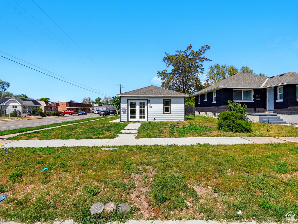 View of front of house with french doors and a front lawn