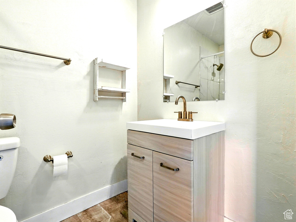 Full bath featuring toilet, wood finished floors, vanity, a shower, and baseboards