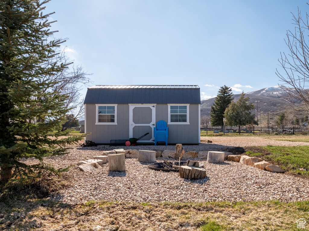 Exterior space featuring an outbuilding, metal roof, a shed, a mountain view, and fence