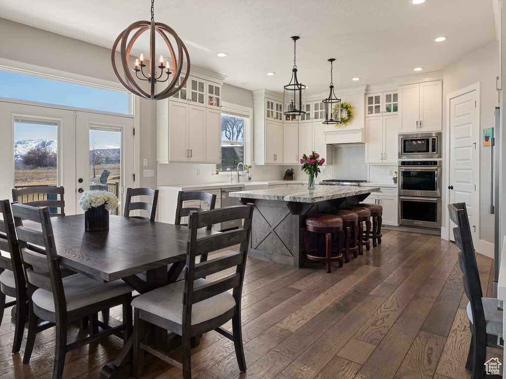 Dining area featuring an inviting chandelier, dark wood-style flooring, french doors, and recessed lighting