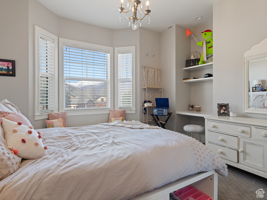 Bedroom featuring an inviting chandelier and dark carpet