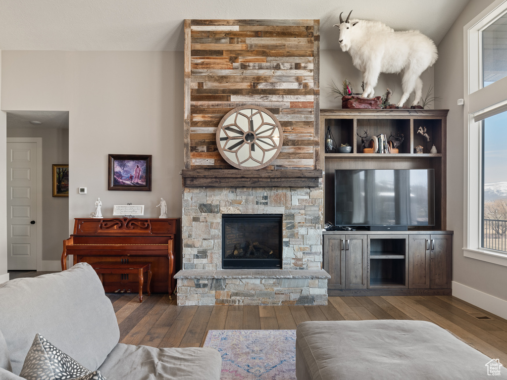 Living area with a fireplace, baseboards, wood finished floors, and plenty of natural light