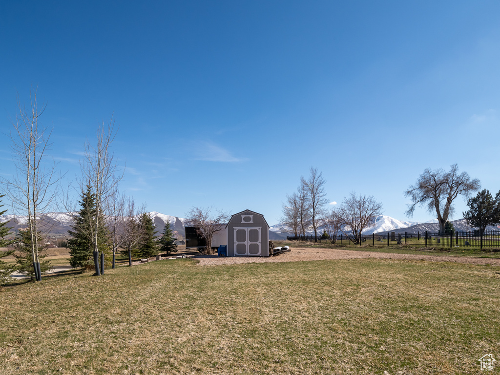 View of yard with fence, a storage unit, a mountain view, and an outdoor structure