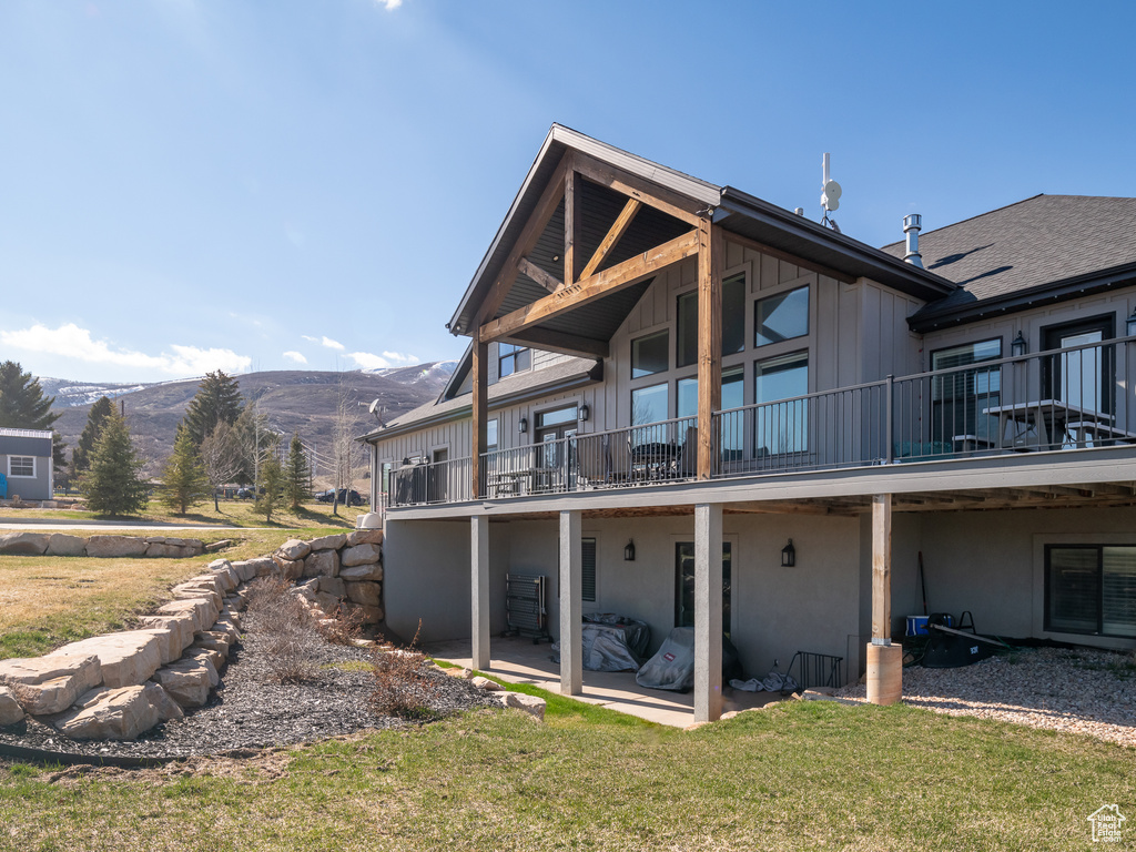 Rear view of property featuring a patio, a mountain view, board and batten siding, and a lawn