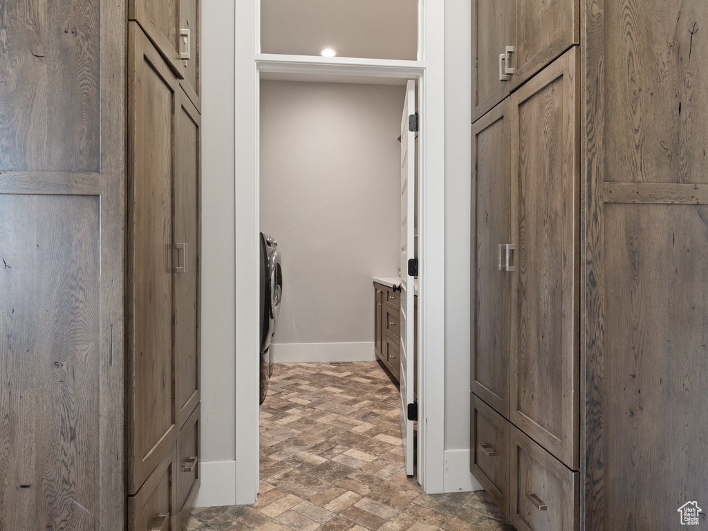 Clothes washing area featuring laundry area, brick floor, and baseboards