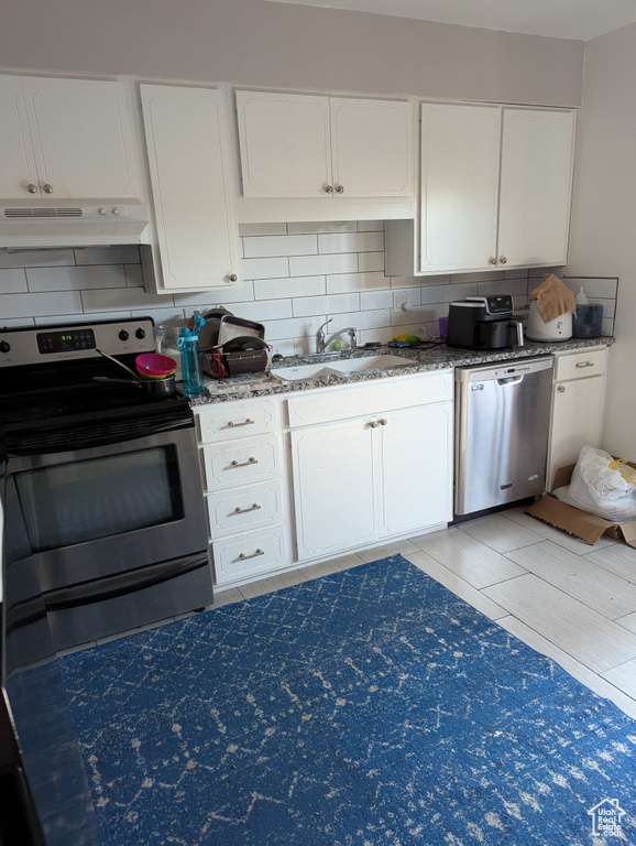 Kitchen featuring stainless steel appliances, a sink, under cabinet range hood, tasteful backsplash, and white cabinets