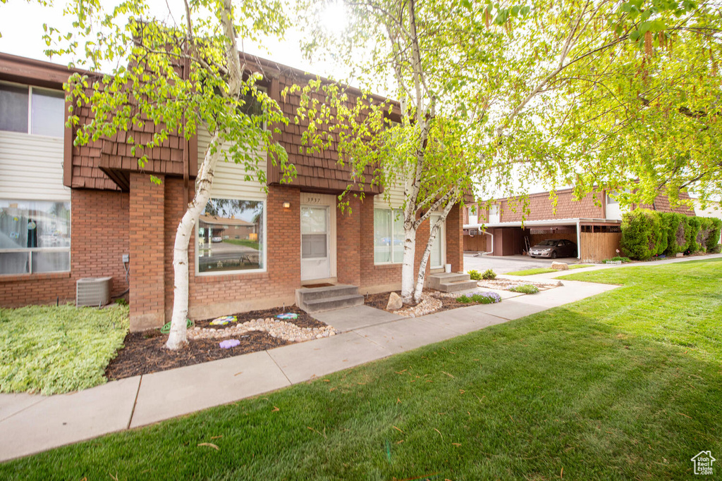 View of property with mansard roof, a front lawn, entry steps, and brick siding