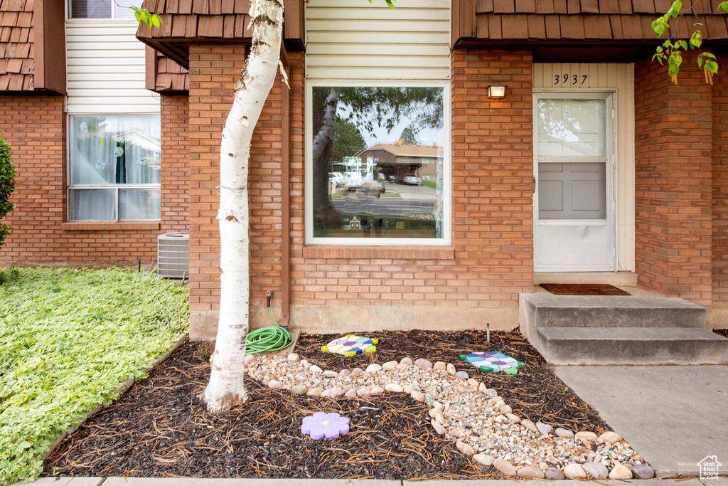 Entrance to property with central AC, mansard roof, and brick siding