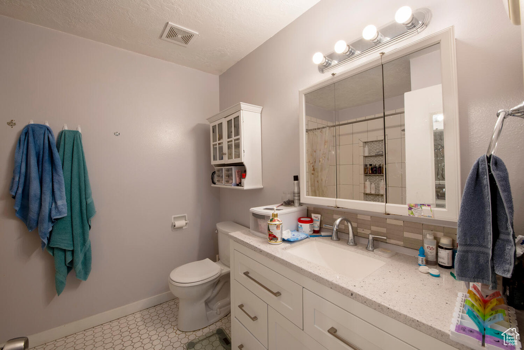 Bathroom with vanity, toilet, visible vents, baseboards, and a shower with shower curtain
