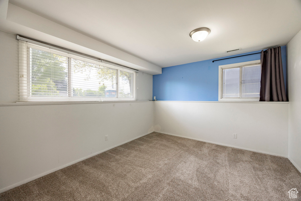 Carpeted empty room featuring visible vents, a healthy amount of sunlight, and baseboards