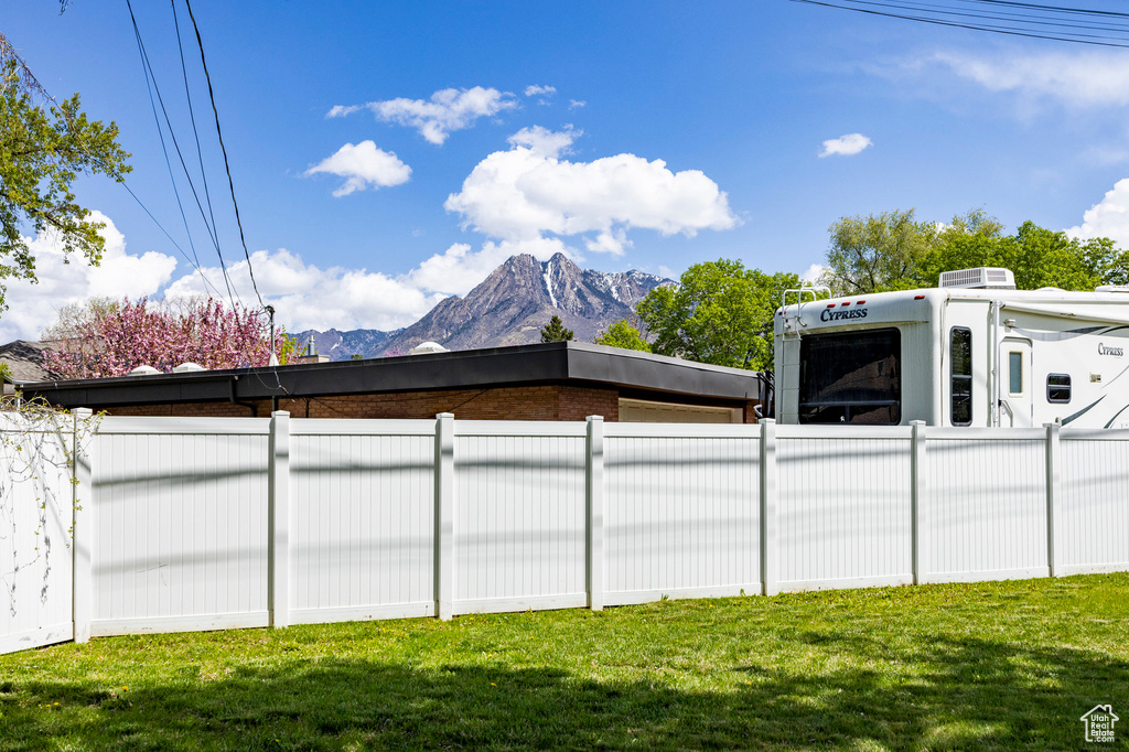 Exterior space featuring fence, a lawn, a mountain view, and brick siding