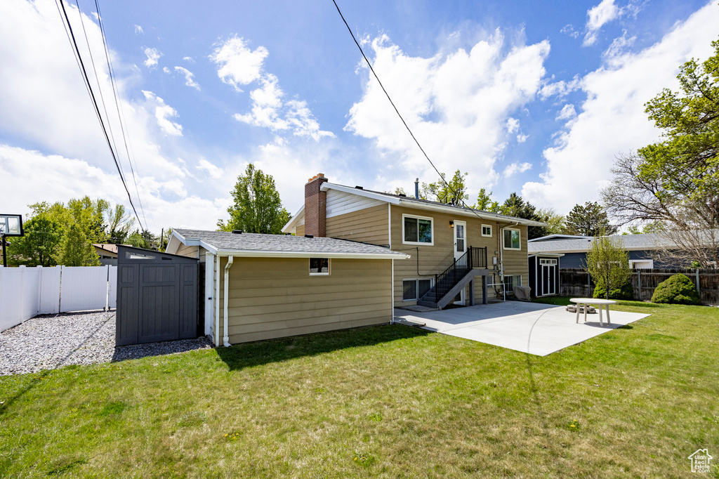 Rear view of property featuring an outbuilding, a storage shed, a fenced backyard, and a patio area