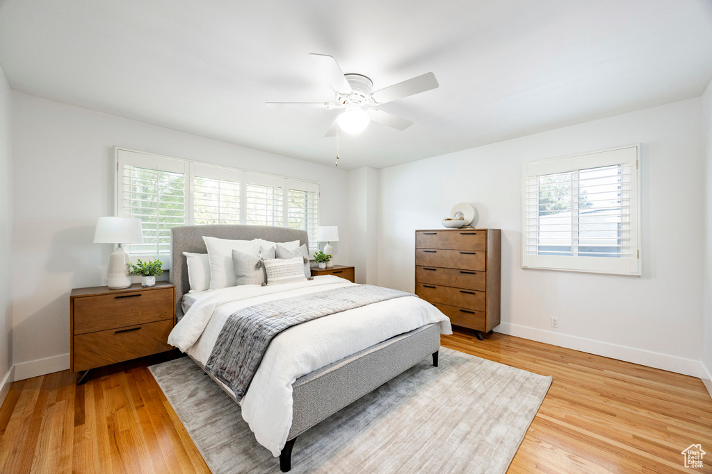 Bedroom featuring baseboards, ceiling fan, multiple windows, and light wood finished floors