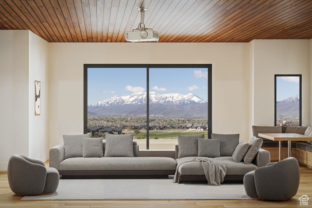 Living area with a mountain view, wood finished floors, wooden ceiling, and healthy amount of natural light