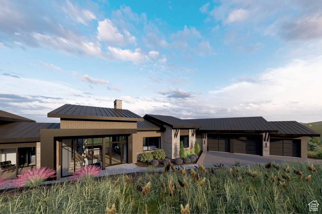 Back of house featuring a standing seam roof, a chimney, an attached garage, and metal roof