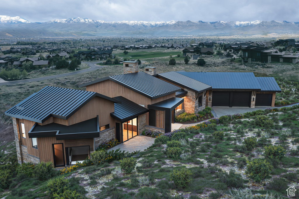 View of front facade featuring a standing seam roof, stone siding, metal roof, a mountain view, and a chimney