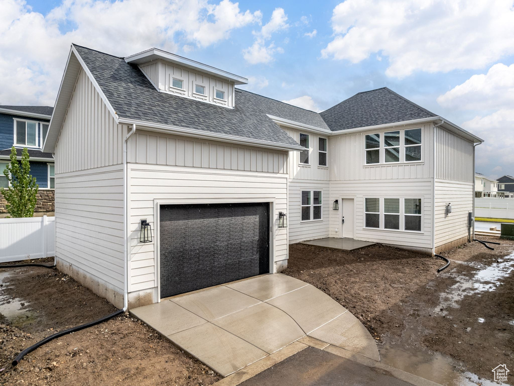 Exterior space with fence, driveway, and roof with shingles