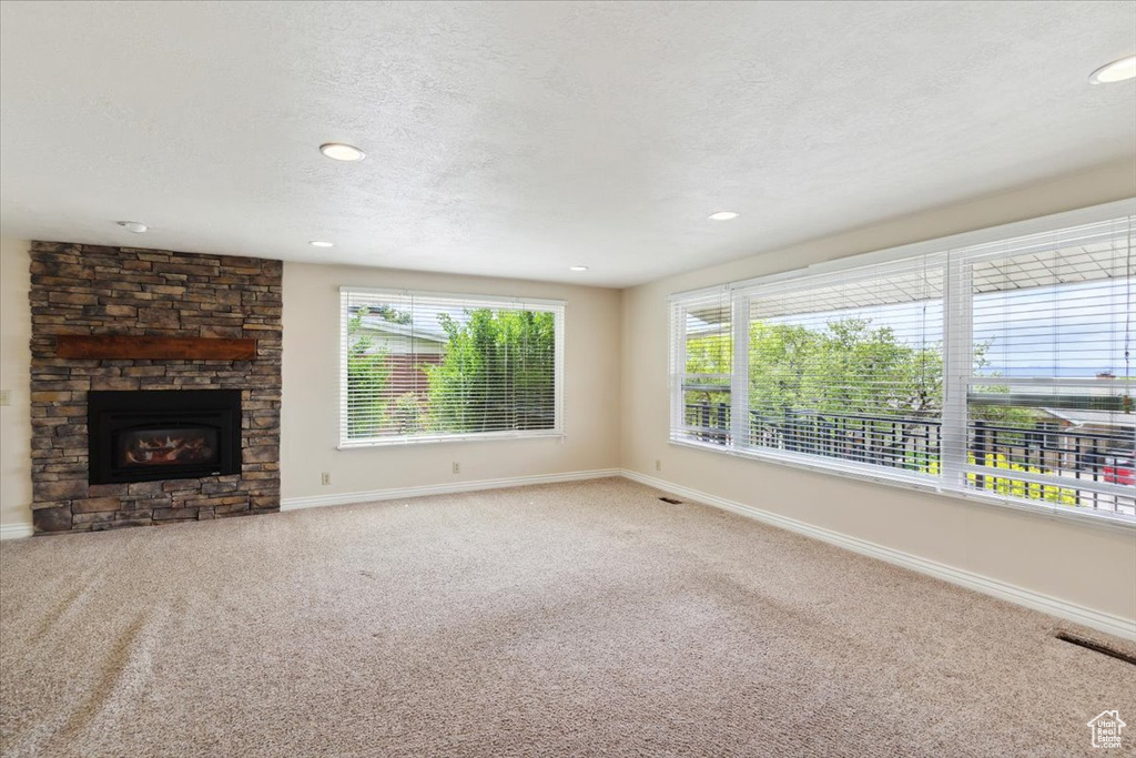 Unfurnished living room with baseboards, carpet flooring, and a textured ceiling