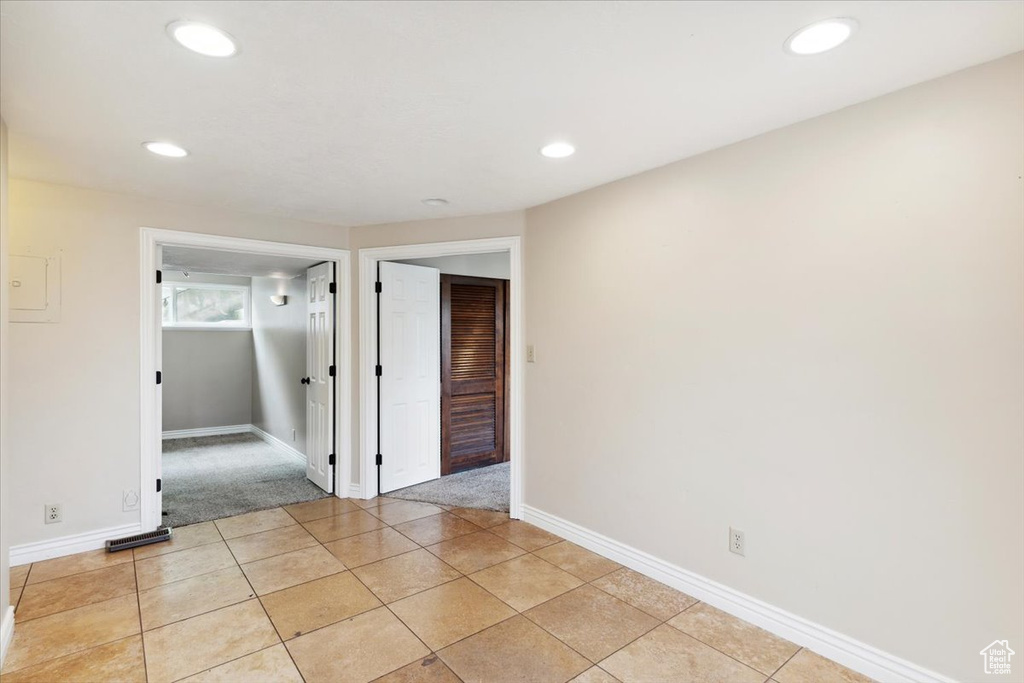 Empty room with recessed lighting, baseboards, light colored carpet, and light tile patterned flooring