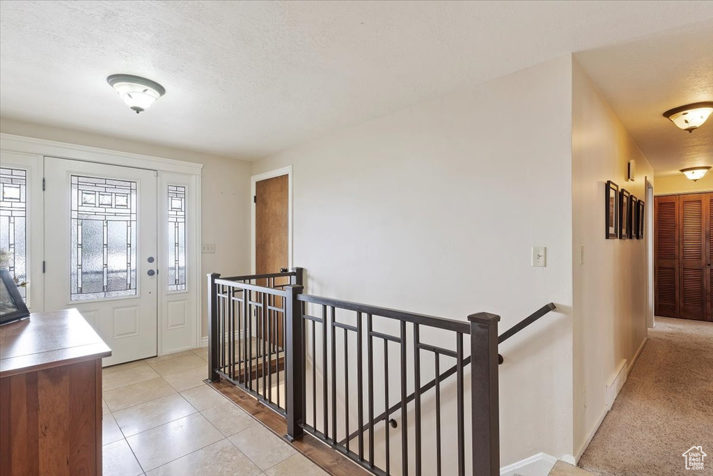 Foyer entrance with baseboards, a textured ceiling, and light tile patterned floors
