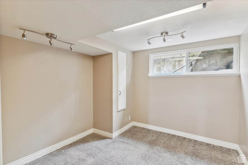 Carpeted spare room with track lighting and baseboards