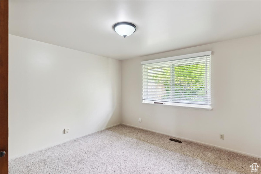 Carpeted spare room featuring visible vents