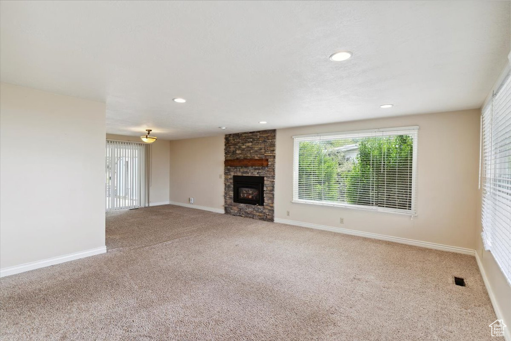 Unfurnished living room with recessed lighting, baseboards, carpet, and a fireplace