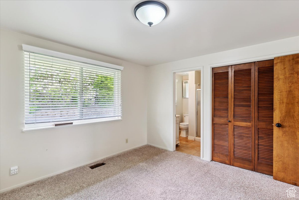 Unfurnished bedroom featuring visible vents, a closet, baseboards, connected bathroom, and carpet
