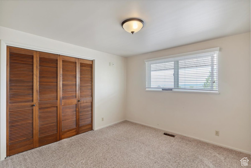 Unfurnished bedroom with carpet floors, baseboards, visible vents, and a closet
