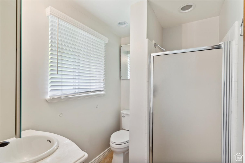 Bathroom featuring a sink, baseboards, a shower stall, and toilet
