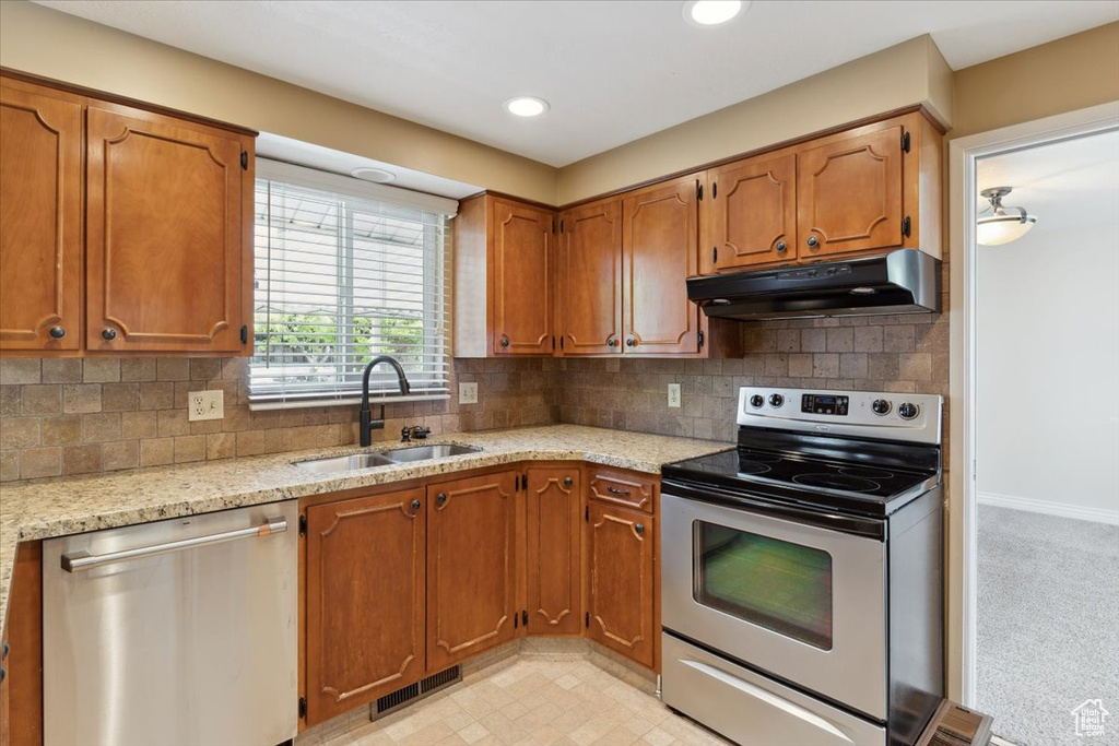 Kitchen with visible vents, under cabinet range hood, brown cabinets, a sink, and stainless steel appliances