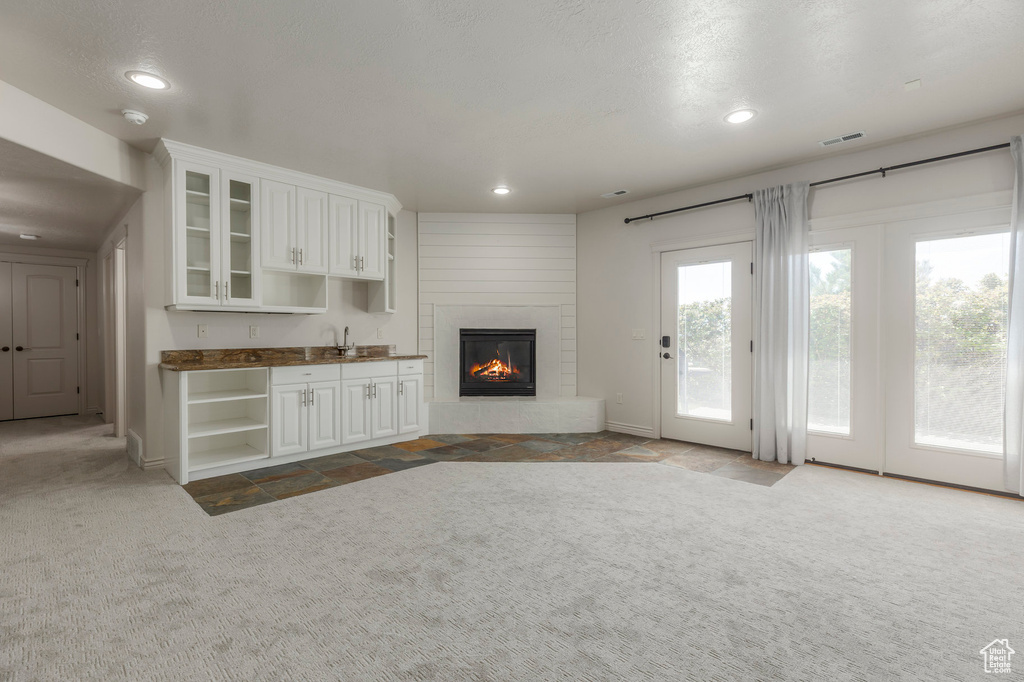 Unfurnished living room featuring recessed lighting, a fireplace, carpet flooring, baseboards, and visible vents