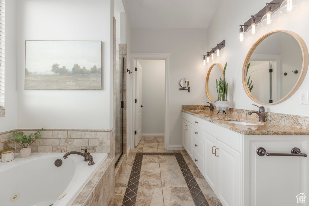 Full bath featuring a sink, double vanity, a stall shower, baseboards, and a jetted tub