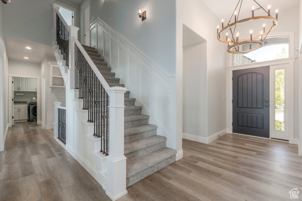 Foyer featuring a towering ceiling, stairway, wood finished floors, and a chandelier