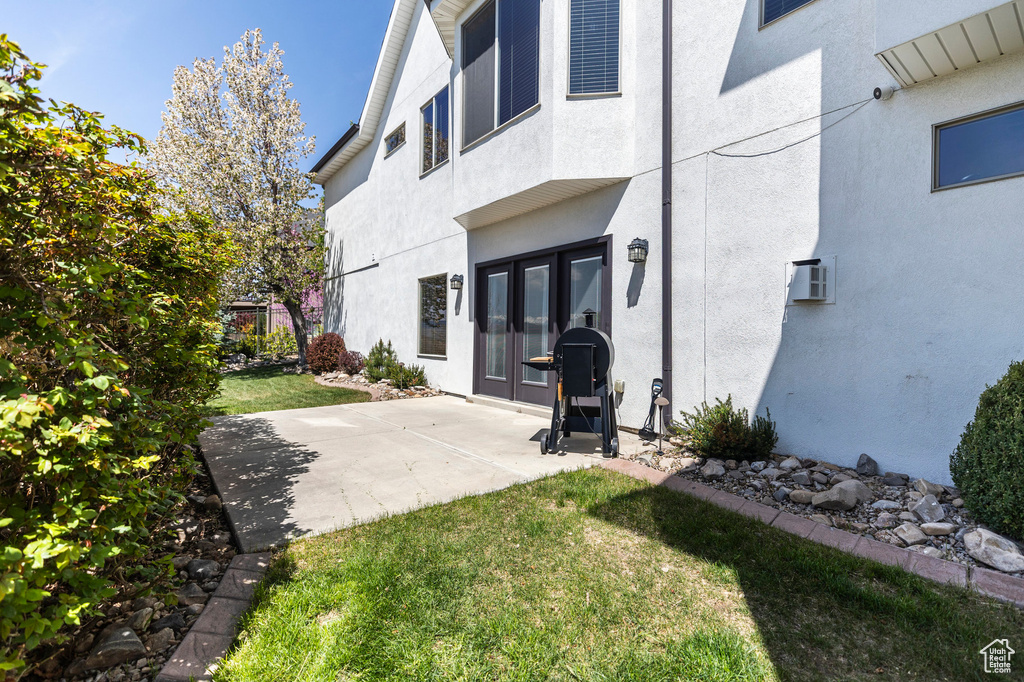 Back of property featuring french doors, stucco siding, a yard, and a patio area