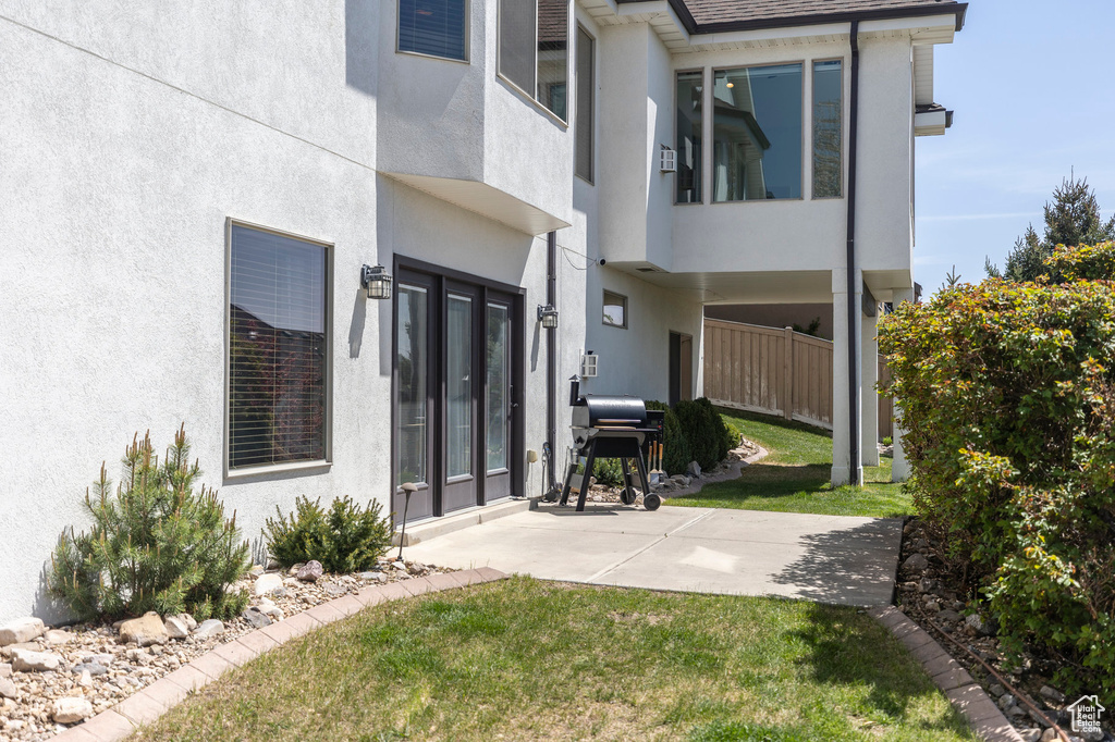 Back of house with stucco siding, a yard, and a patio