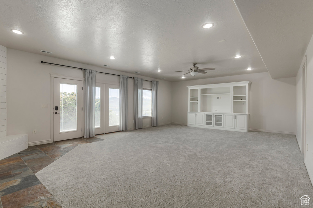 Unfurnished living room featuring recessed lighting, stone tile floors, a ceiling fan, visible vents, and baseboards