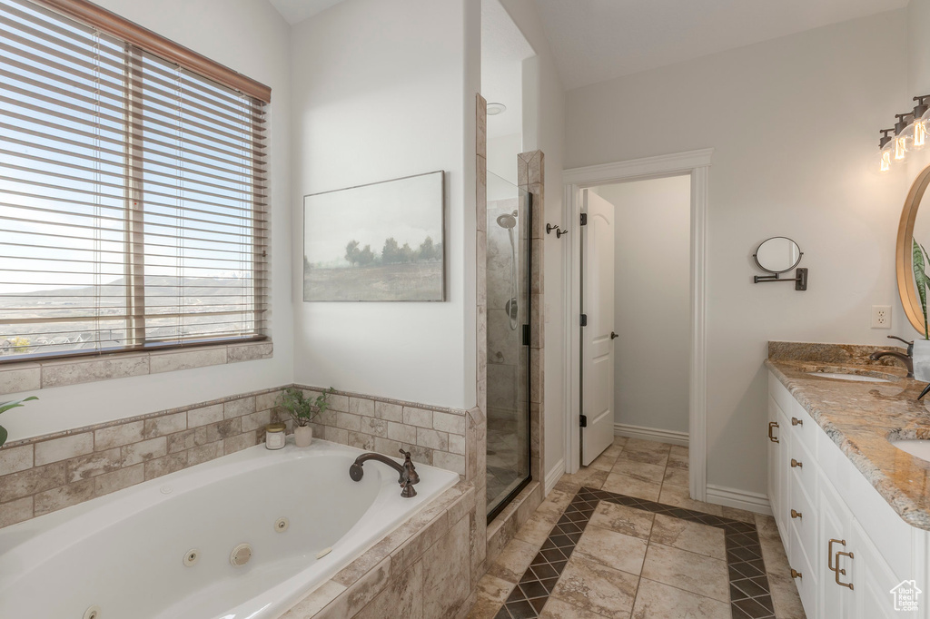 Bathroom featuring a shower stall, a sink, double vanity, baseboards, and a tub with jets