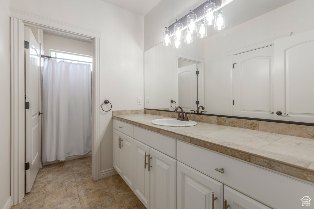 Full bathroom with stone finish floor, vanity, and baseboards
