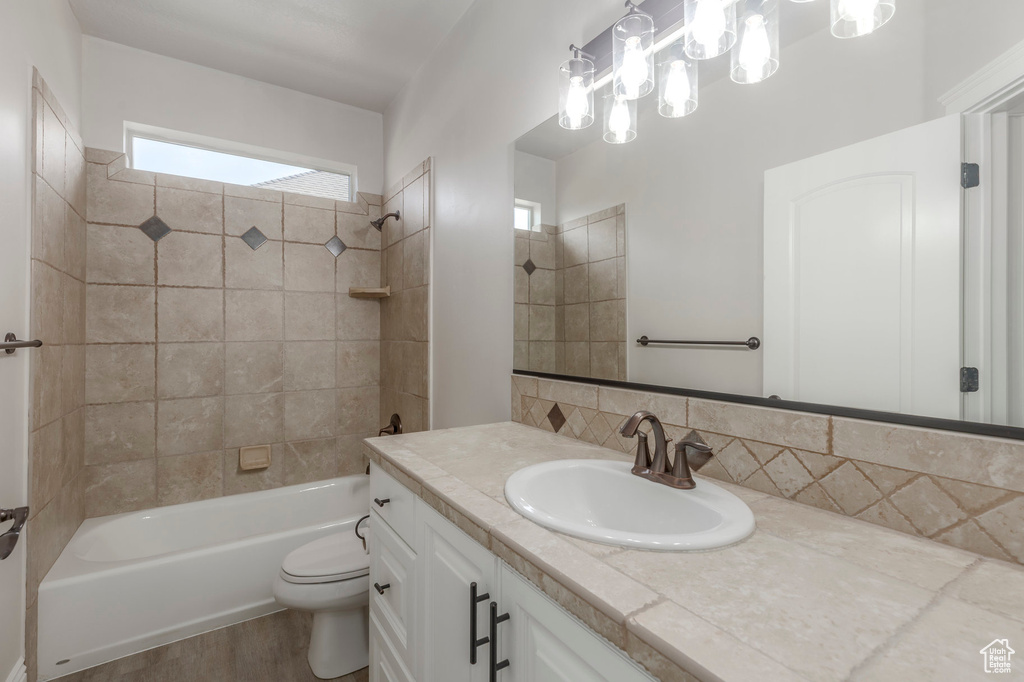Bathroom featuring vanity, decorative backsplash, shower / bathtub combination, toilet, and wood finished floors