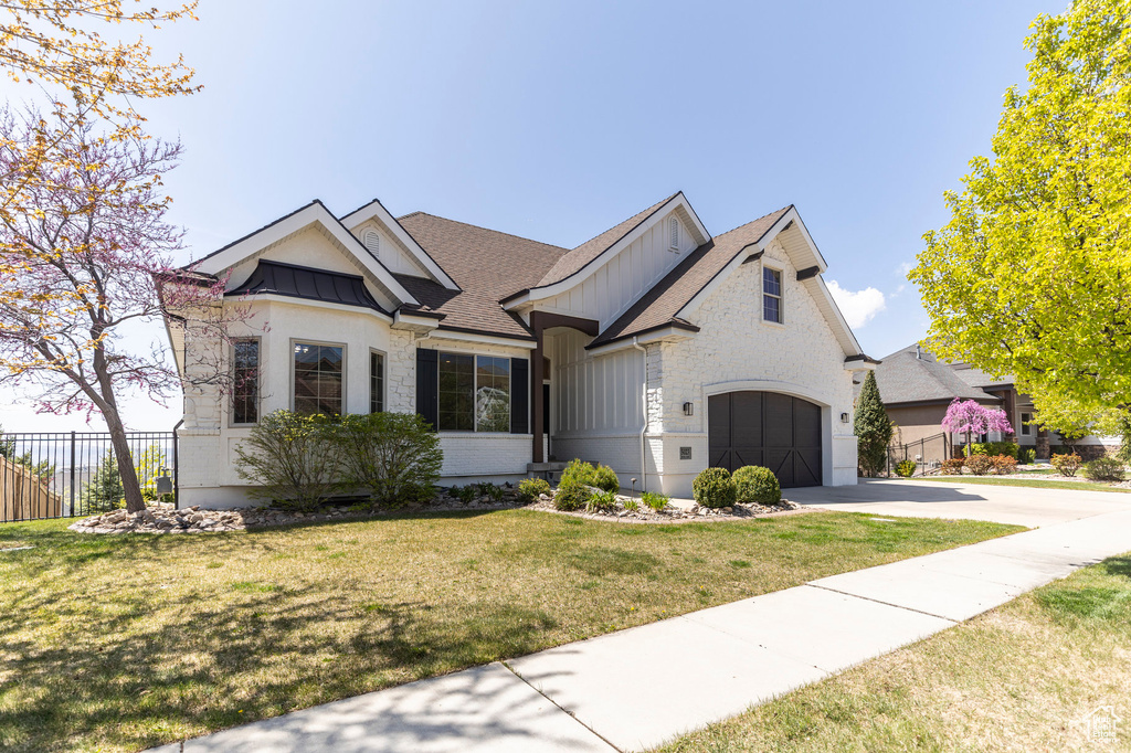 View of front of home featuring a front lawn, a shingled roof, driveway, board and batten siding, and fence