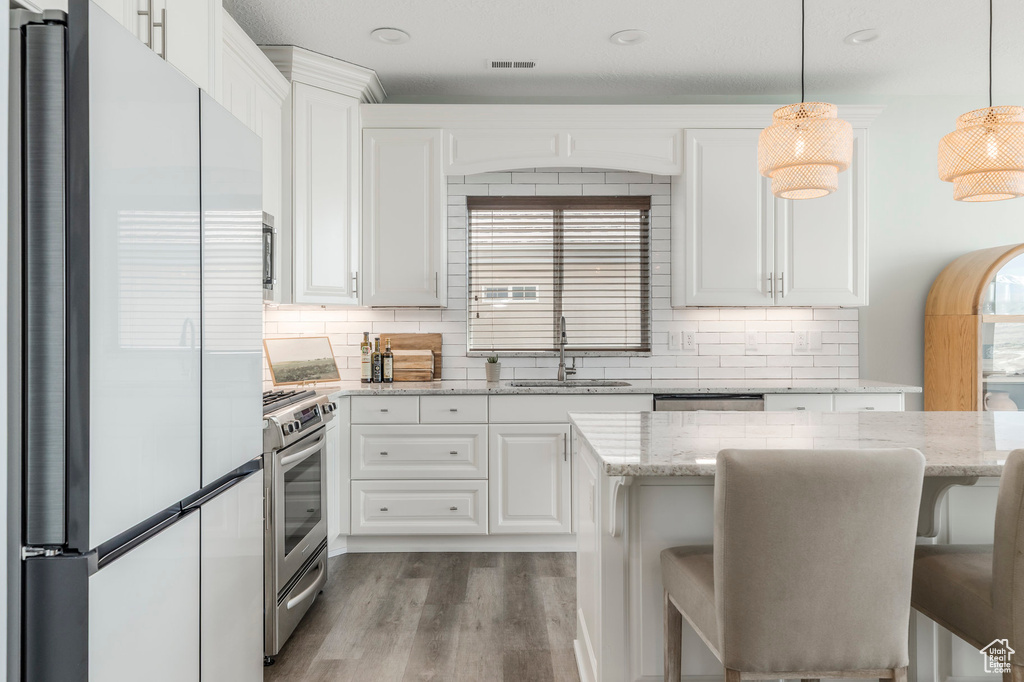 Kitchen featuring tasteful backsplash, wood finished floors, stainless steel appliances, and a sink