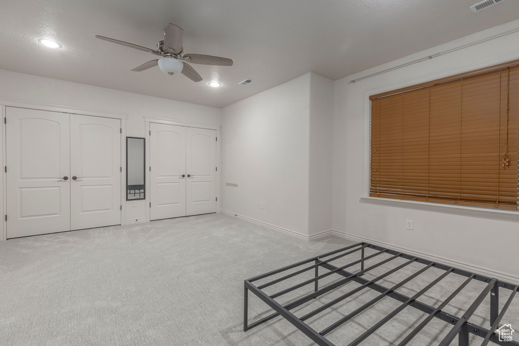 Unfurnished bedroom with recessed lighting, two closets, ceiling fan, baseboards, and carpet floors
