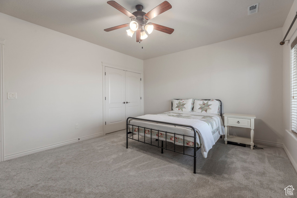 Carpeted bedroom with a ceiling fan, visible vents, a closet, and baseboards
