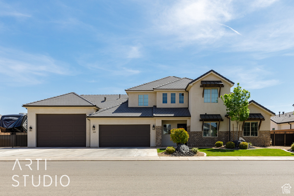 View of front of home with stucco siding, brick siding, fence, concrete driveway, and an attached garage